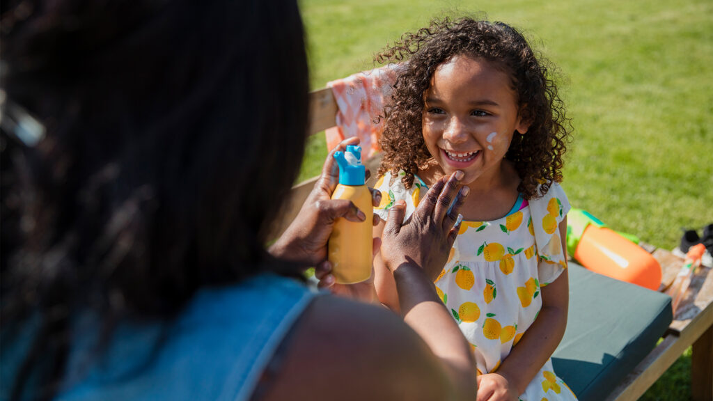 Person putting sunscreen on a kid.