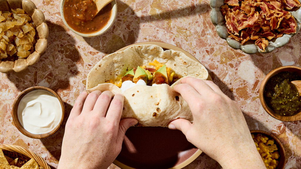 Person wrapping a breakfast burrito.