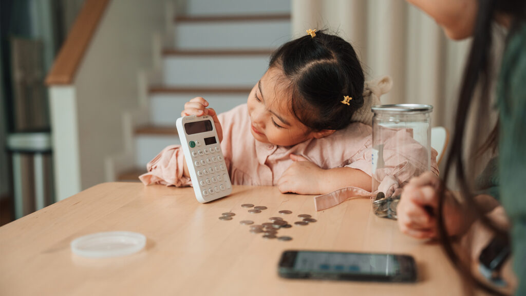 Kid using a calculator to count coins.