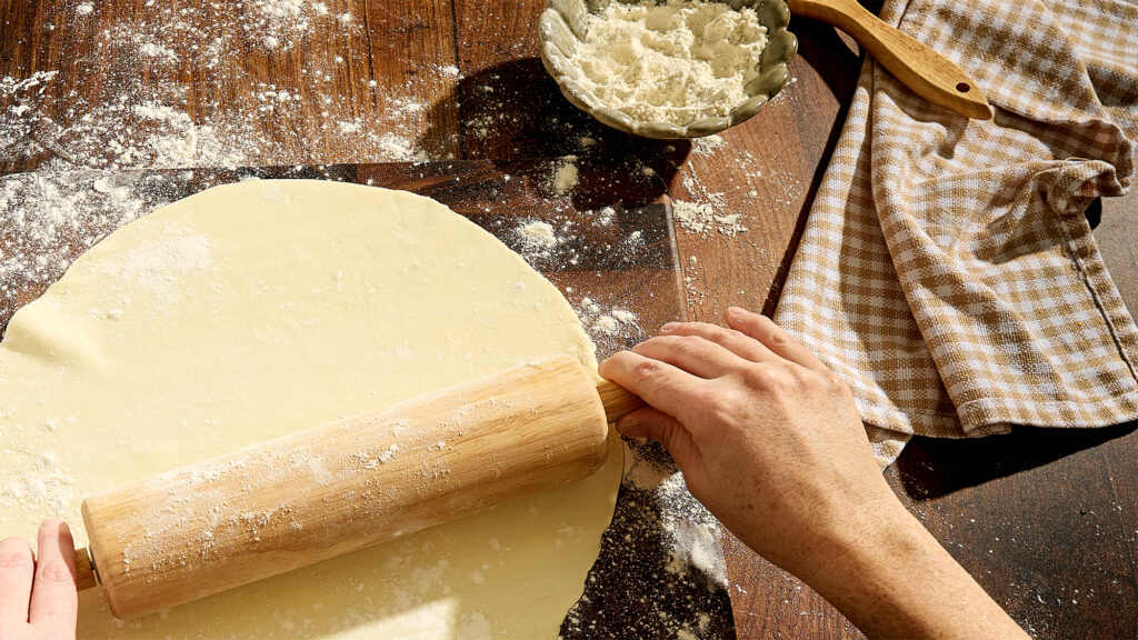 Person rolling pie crust.
